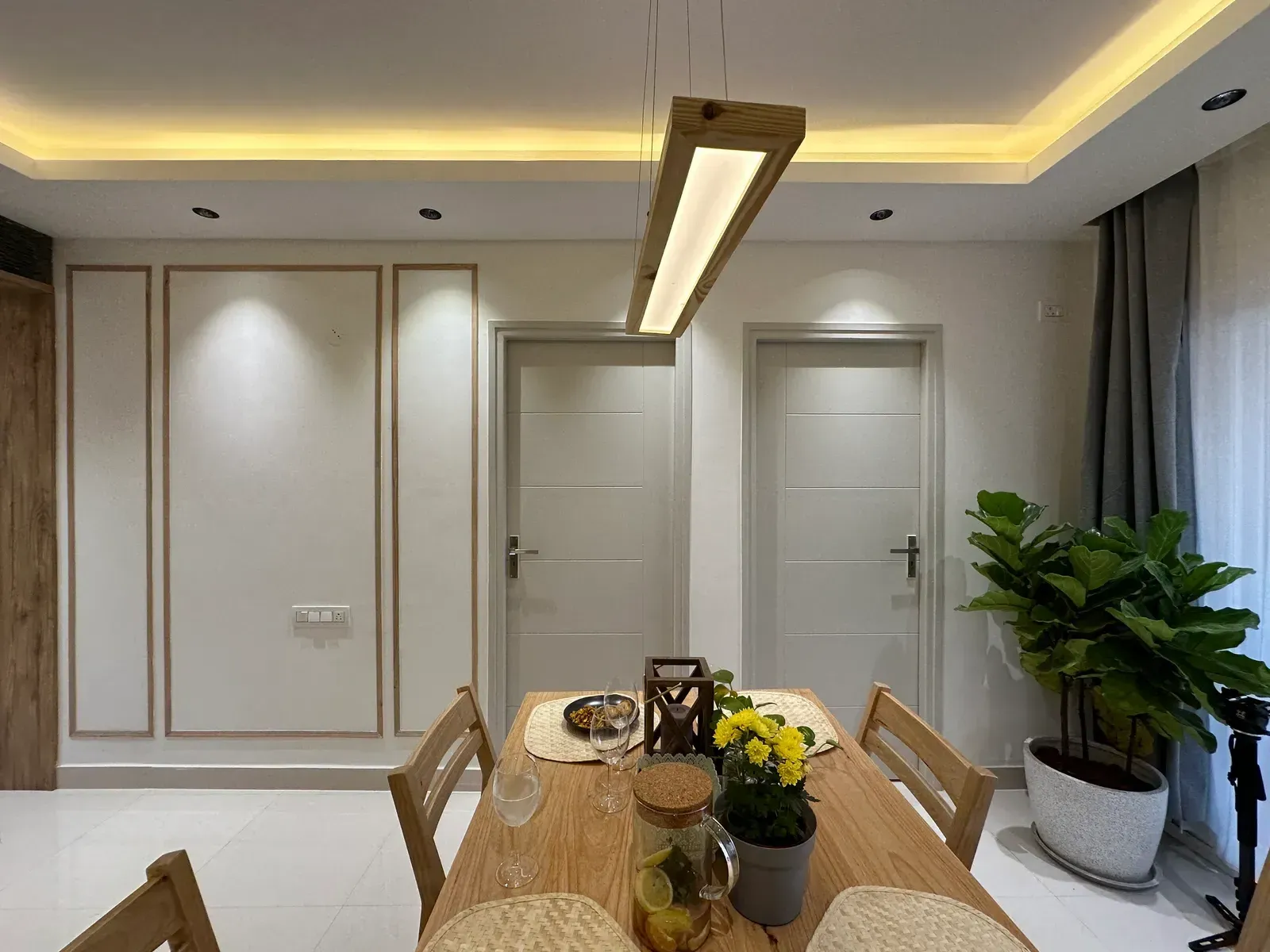 Dining table under a linear oak pendant light — The Aakar
